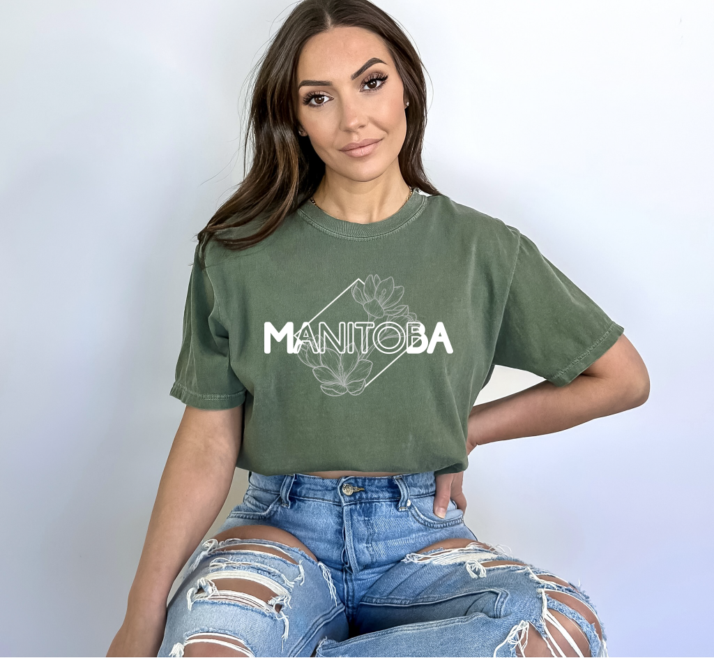 Woman wearing a green t-shirt with 'Manitoba' printed on it against a white background